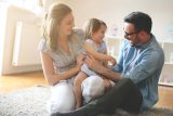 Two adults and a toddler play together in a healthy indoor environment.