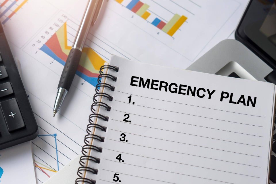 Open notebook labeled Emergency Plan on desk: storm-proofing your home tips.