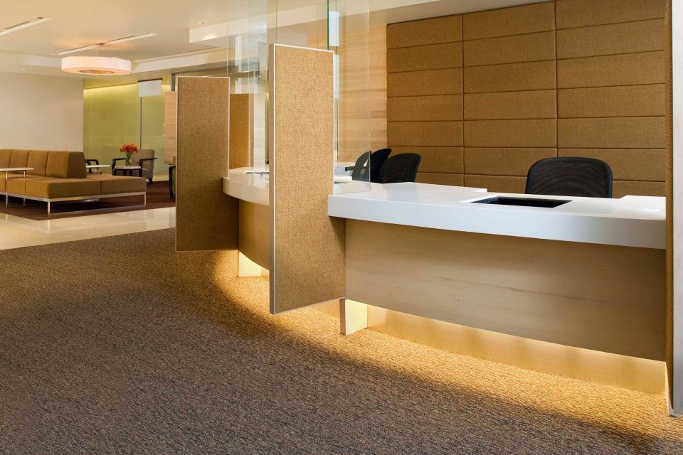 Modern office reception with carpet cleaning services, curved desks, and chairs.
