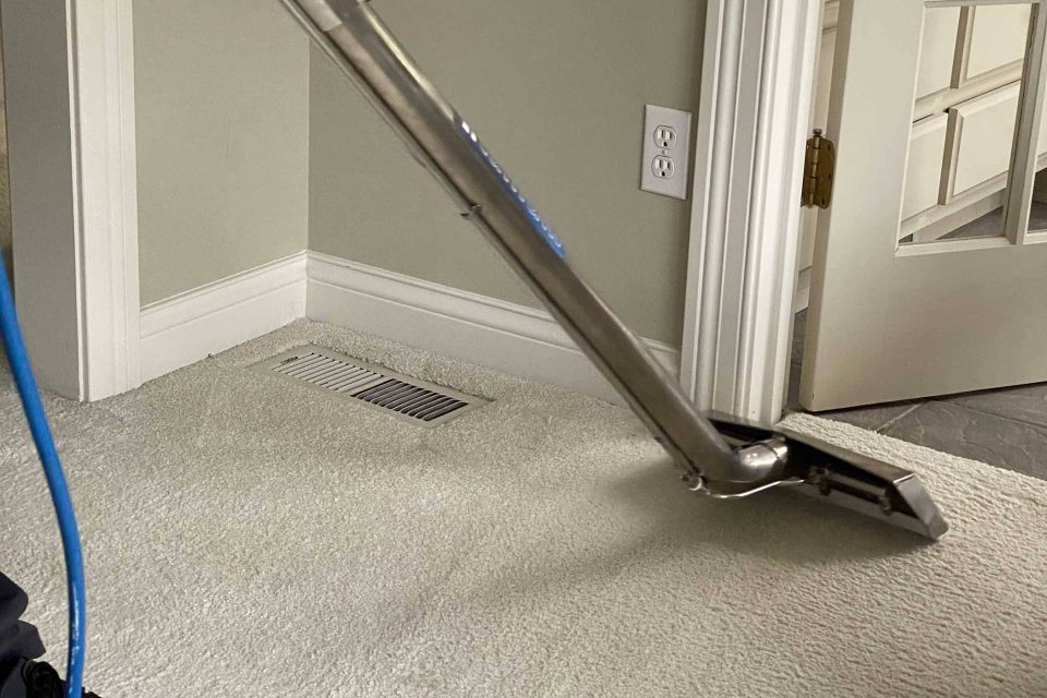 Carpet cleaning services using a steam cleaner in a residential room.