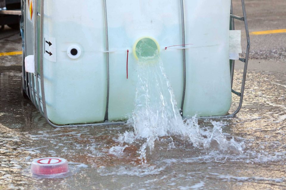 Water spills from a large container needing biohazard cleanup.