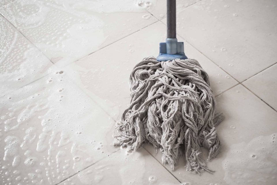 Post-construction mopping a soapy, wet, white tiled floor.